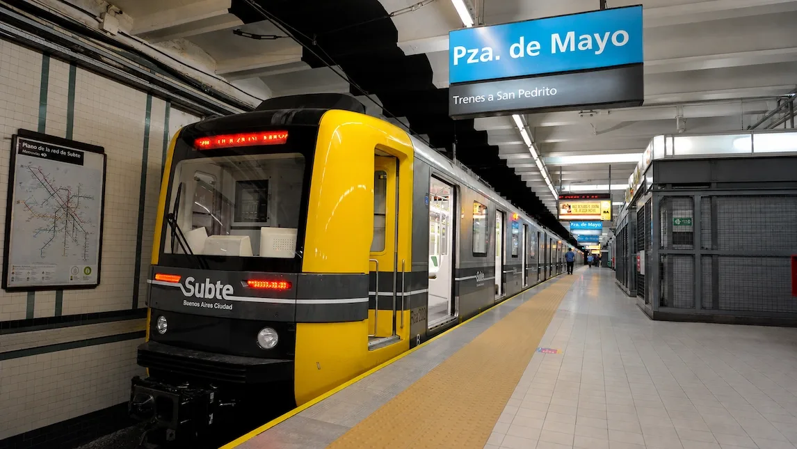 A yellow-and-black Subte train stopped at the Plaza de Mayo platform in Buenos Aires.