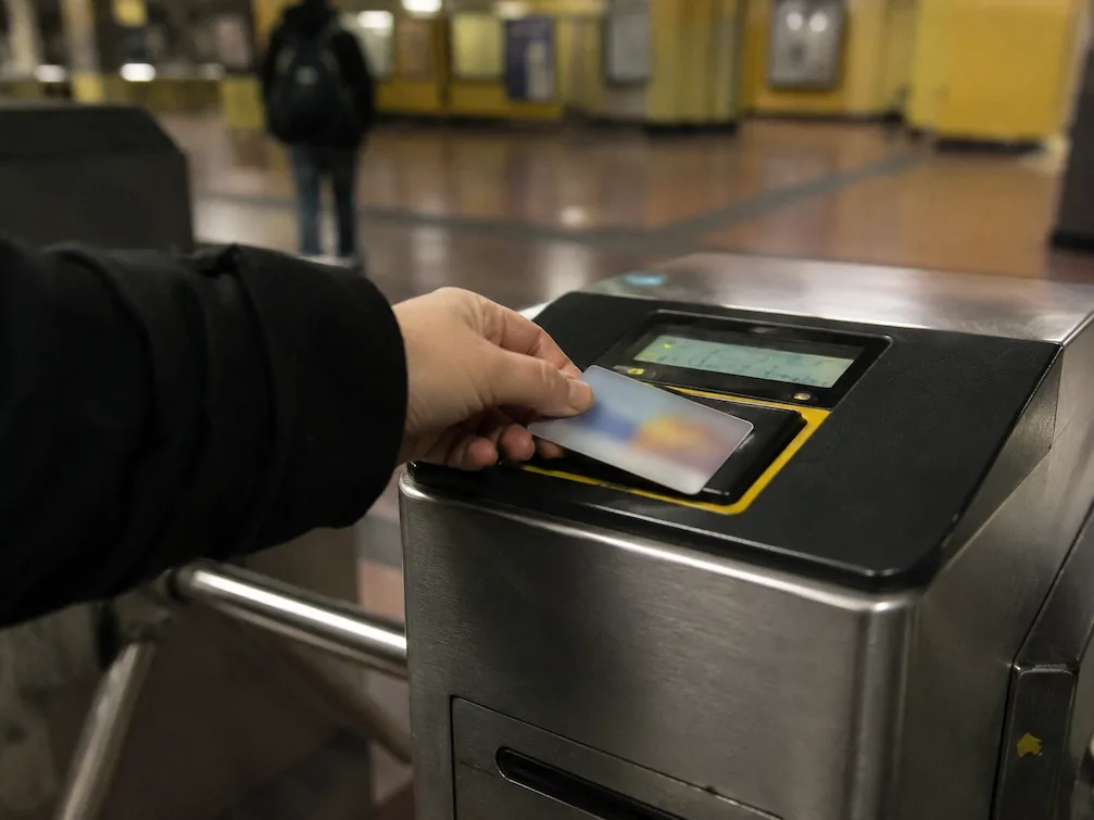 A hand taps a transit card on the reader of a Buenos Aires Subte turnstile