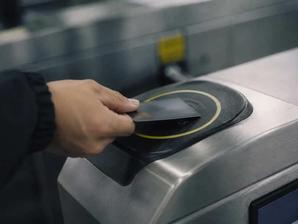 A hand taps a transit card on the reader of a Sao Paulo Metro turnstile