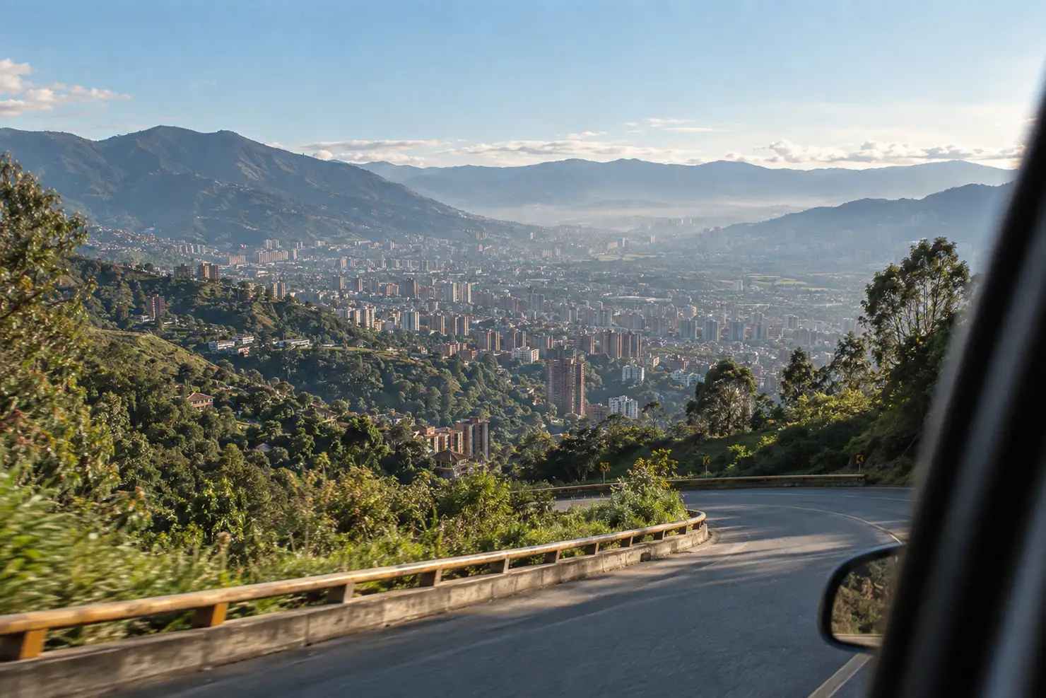 The road down from Rionegro into the Aburrá valley, Medellín spread out below in late-afternoon haze
