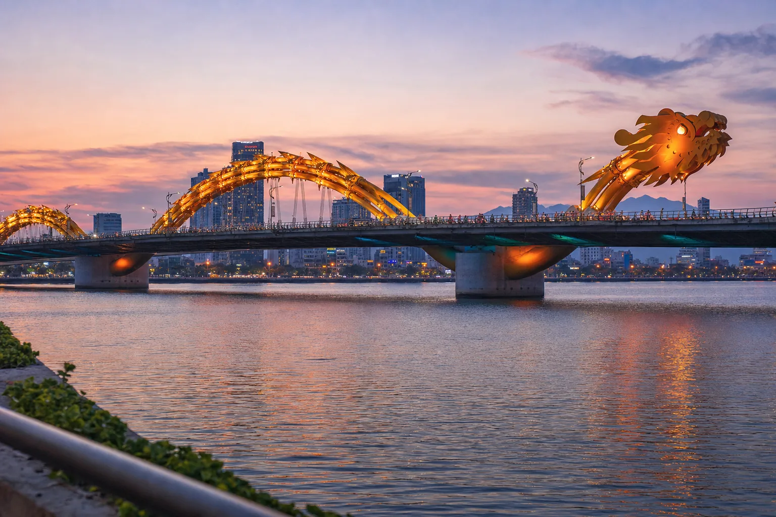 The Dragon Bridge lit up over the Han River in central Da Nang at dusk, with the Hải Châu skyline behind it